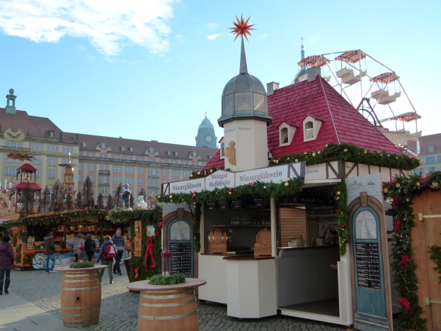 Ein lebendiger Weihnachtsmarkt in Nürnberg, Deutschland, mit Menschen um geschmückte Stände, Gebäude, ein Riesenrad und eine Tafel auf der rechten Seite.