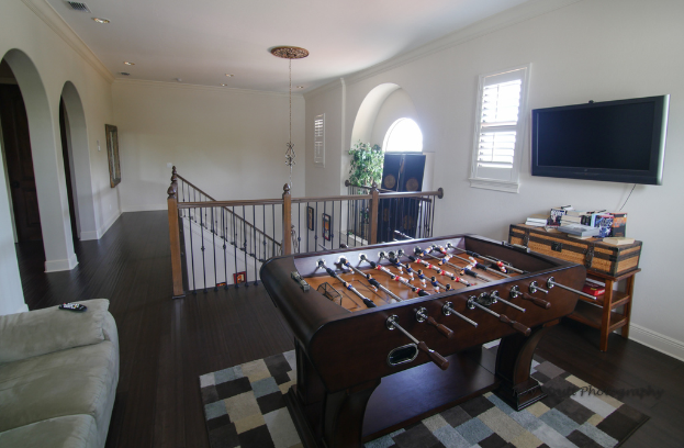 Ein Tischfußball und ein Fernseher sind in der Mitte einer Treppe platziert, mit einer Couch auf der linken Seite.
