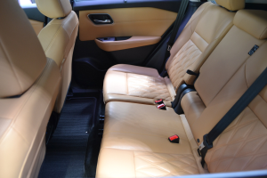 Innenraum eines Autos mit braunen Ledersitzen, Sicherheitsgurten, Türen, Fenstern und anderen Gegenständen, die einen luxuriösen Look vermitteln.