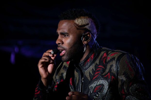 DJ Khaled trägt eine schwarze und rote Jacke und singt auf der Bühne beim Coachella Valley Music and Arts Festival 2018, vor einem dunklen Hintergrund.