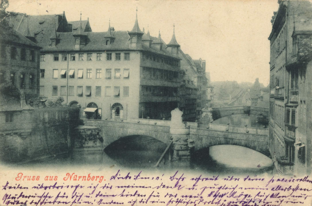Ein altes Foto einer Brücke, die einen Fluss in Nürnberg, Deutschland, überspannt, mit umgebenen Gebäuden und einem sichtbaren Himmel, mit Text am unteren Bildrand.