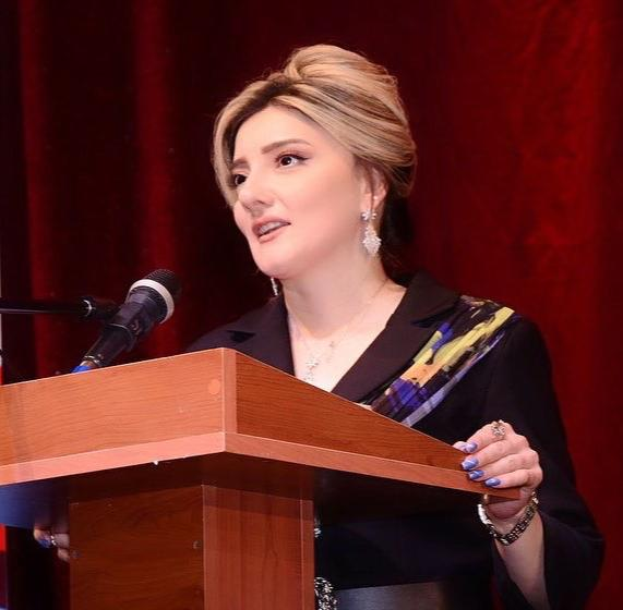 Eine Frau steht an einem Podium mit einem Mikrofon, wahrscheinlich spricht sie über Frauenrechte.