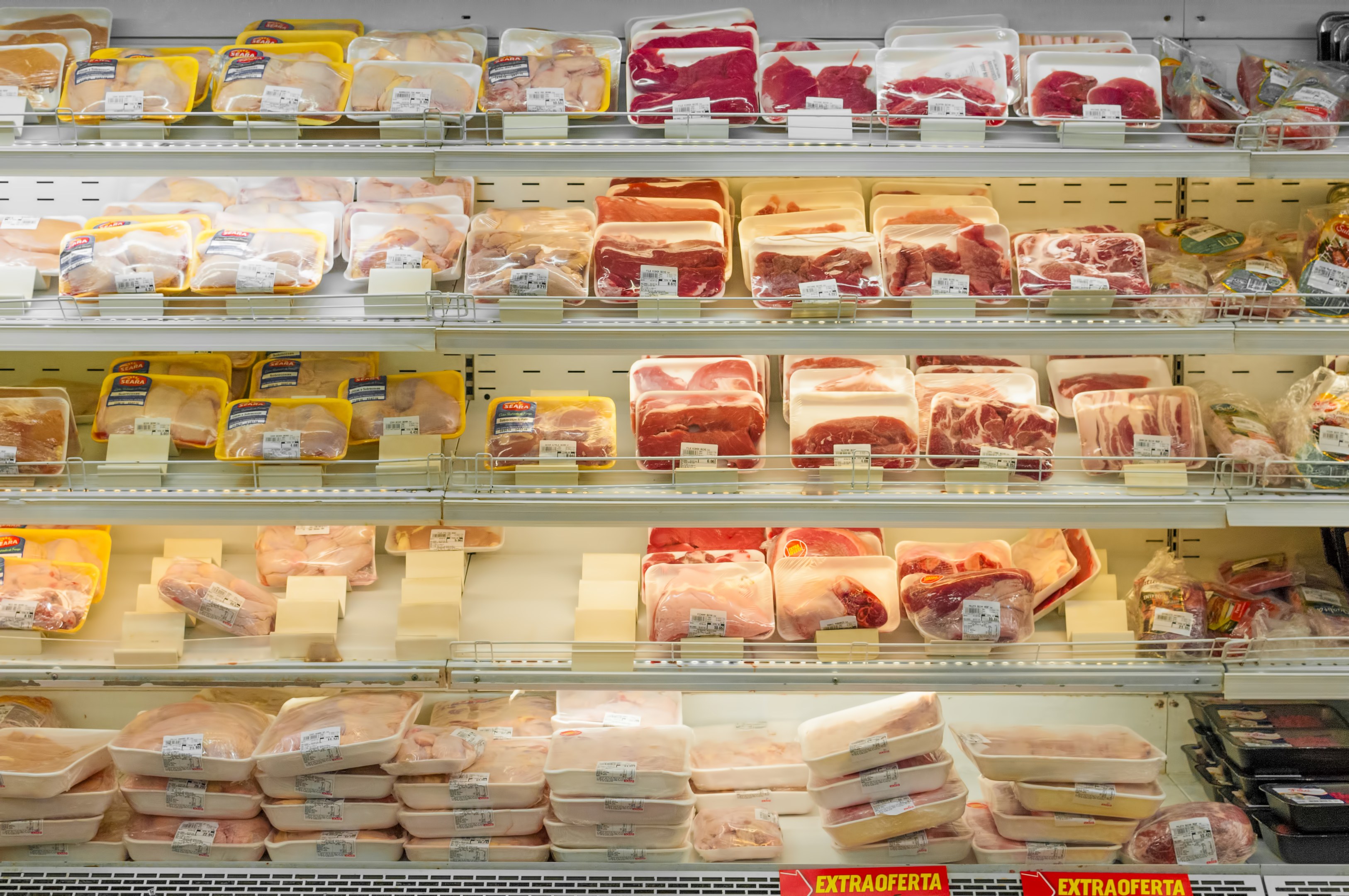 Ein gut organisierter Fleischabschnitt im Supermarkt mit verschiedenen Fleischsorten ordentlich auf Regalen angeordnet und mit Preisschildern versehen.