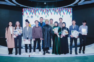 Gruppe von Menschen auf einer Bühne mit Blumensträußen und Urkunden, im Hintergrund ein "Jugend-Solar-Awards 2019"-Plakat