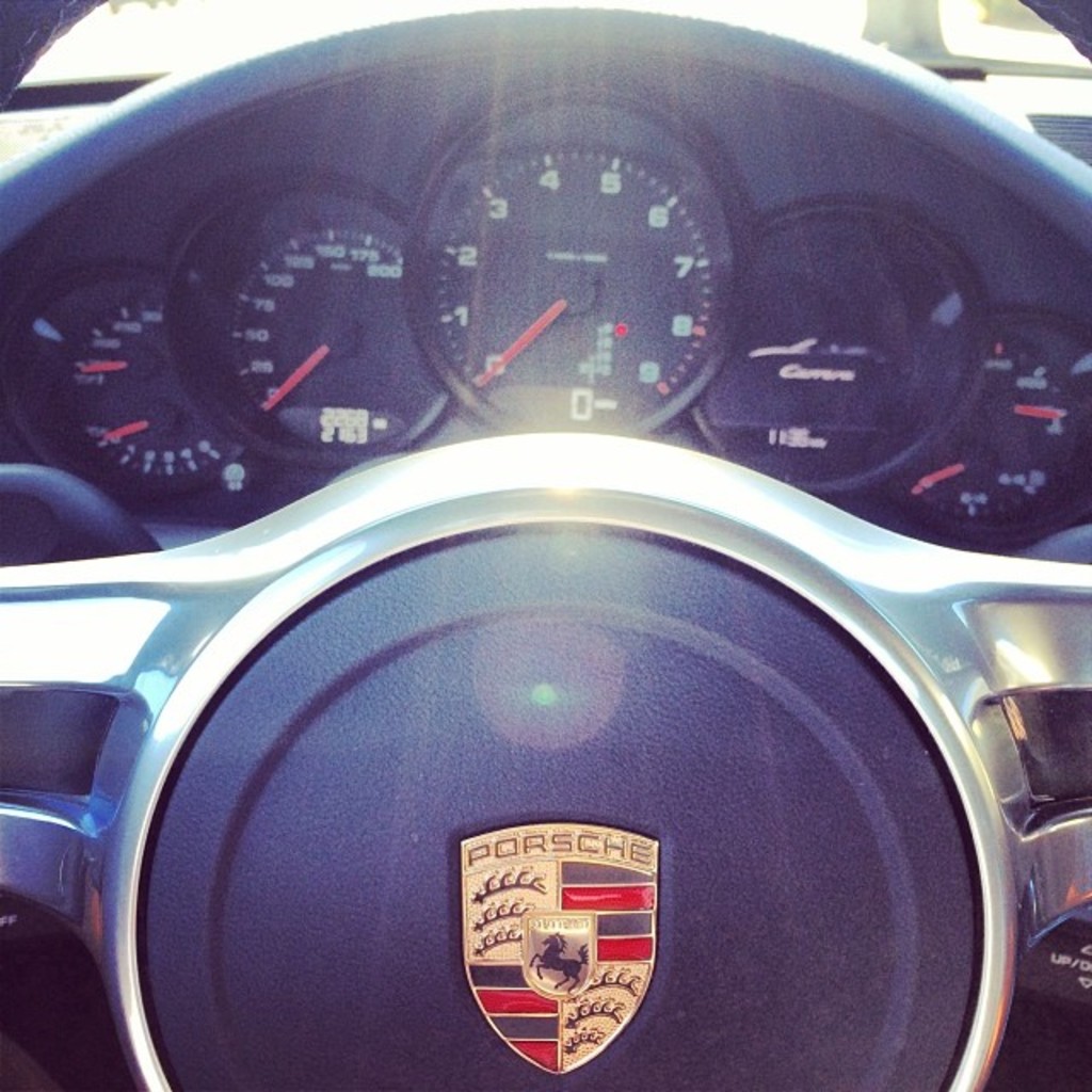 Ein Nahaufnahme-Bild eines Porsche-Fahrzeugs mit einem Blick auf das Armaturenbrett und das Lenkrad.