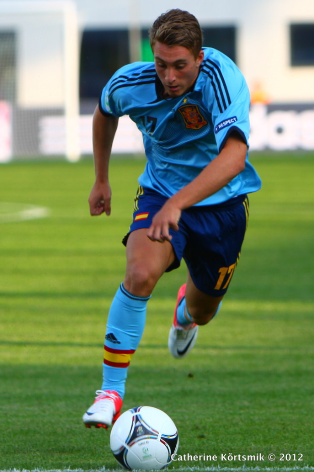 Mann in blauem T-Shirt spielt Fußball auf einem Feld.
