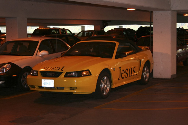 Ein vollbesetzter Parkplatz mit zahlreichen geparkten Autos vor einem Gebäude.