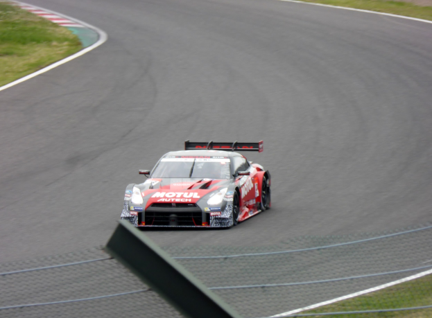 Ein Nissan GT-R Nismo GT3 Rennauto auf der Nürburgring 24 Stunden Rennstrecke mit grünem Gras auf beiden Seiten.