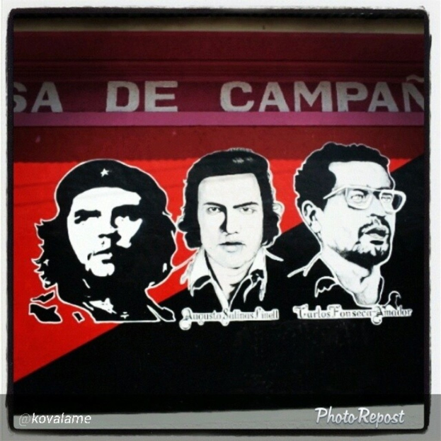 Ein schwarzes und rotes Plakat mit drei Männern und mehreren Namen.