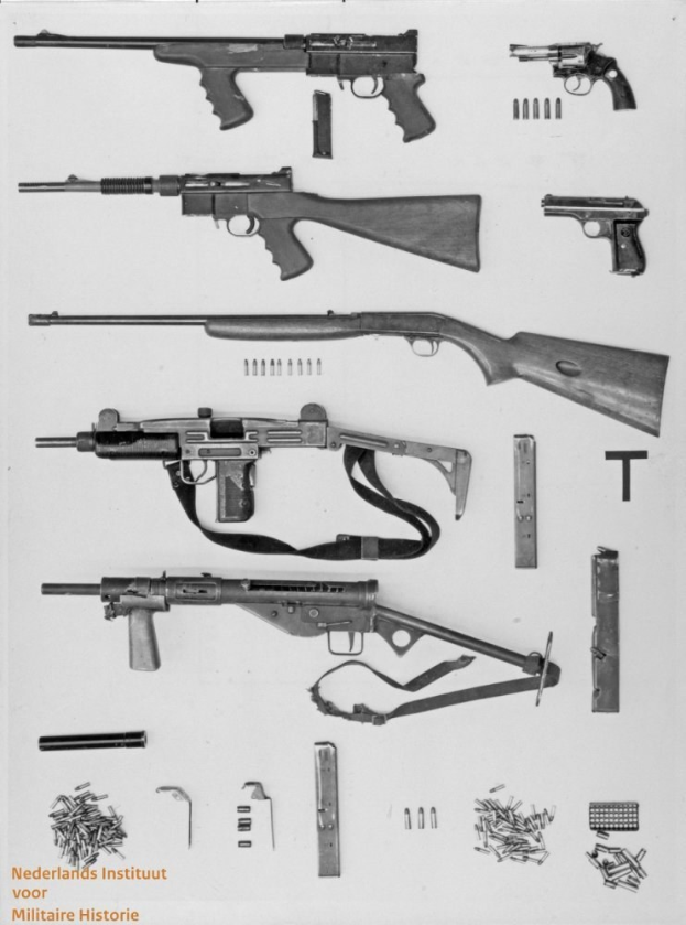 Schwarz-weiß-Foto von verschiedenen Waffen, Munition und verstreuten Gegenständen mit Text unten.