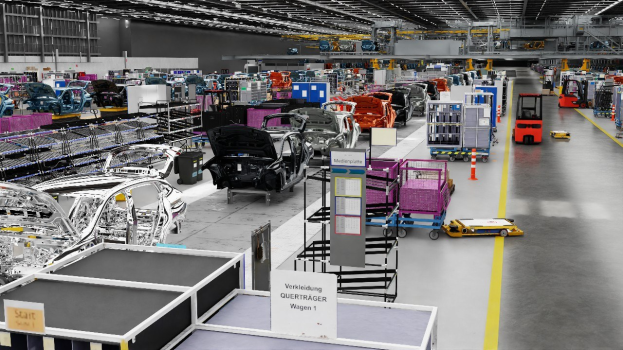 Große Fabrik-Montageband mit zahlreichen Autos in der Produktion, metallische Strukturen auf beiden Seiten, Fahrzeuge auf dem Boden, eine Wand im Hintergrund und an der Decke angebrachte Lampen.