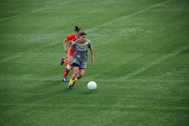Mehrere Frauen umringen einen Ball auf dem Boden.