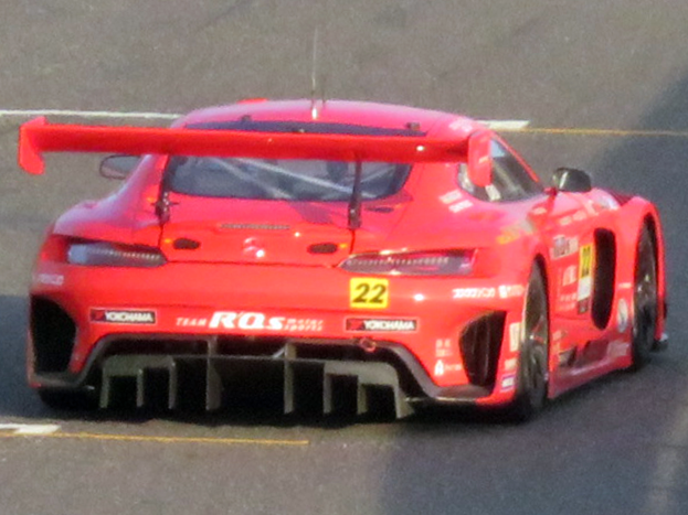 Ein leuchtend roter Porsche 911 GTS Rennauto mit schlankem, aerodynamischem Design, niedrigem Profil, breiter Basis, großem Spoiler, großem Heckflügel und großen schwarzen Rädern, das auf einer Rennstrecke fährt.