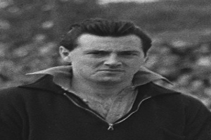 Ein Schwarz-Weiß-Foto des Schauspielers James Dean in einer Kapuzenjacke, der im Vordergrund steht und ein unscharfer Hintergrund zu sehen ist.