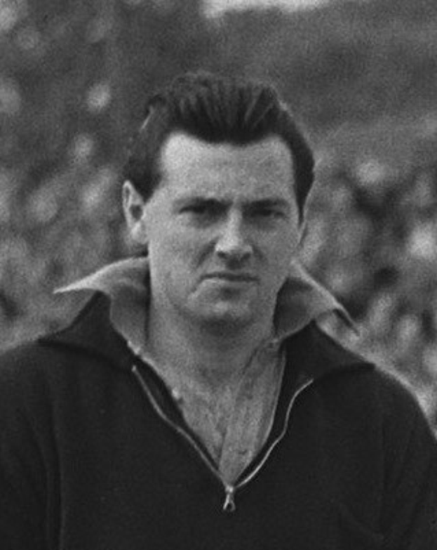 Ein Schwarz-Weiß-Foto des Schauspielers James Dean in einer Kapuzenjacke, der im Vordergrund steht und ein unscharfer Hintergrund zu sehen ist.