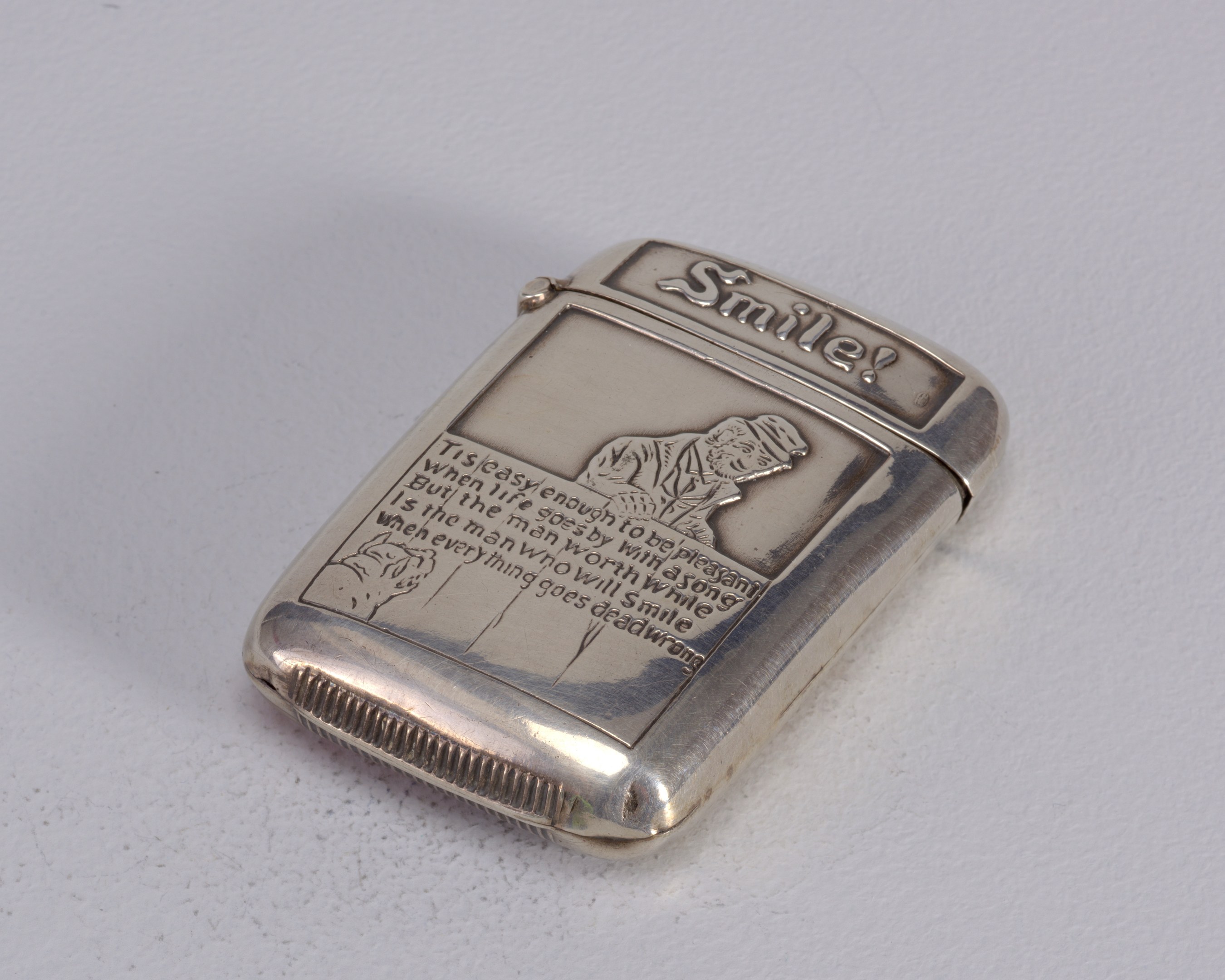 Silbernes Zigarettenetui mit einem Männerporträt darauf, auf einer weißen Oberfläche platziert, mit der Aufschrift "Feuerzeug".