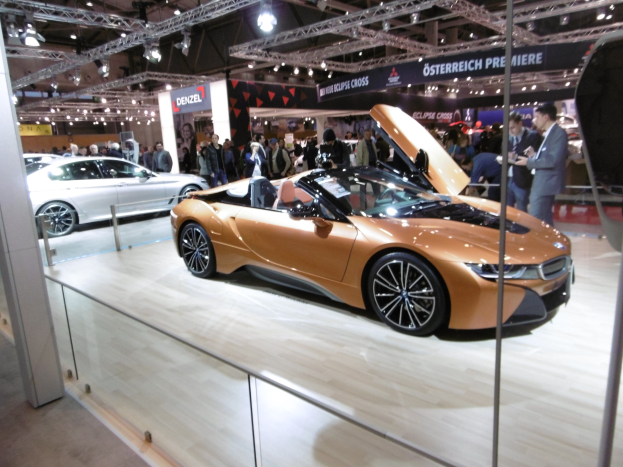 Schwarzer BMW i8 Roadster mit glänzender Lackierung und Chromakzenten, der auf der IAA in Frankfurt präsentiert wird und von formell gekleideten Gästen umgeben ist.