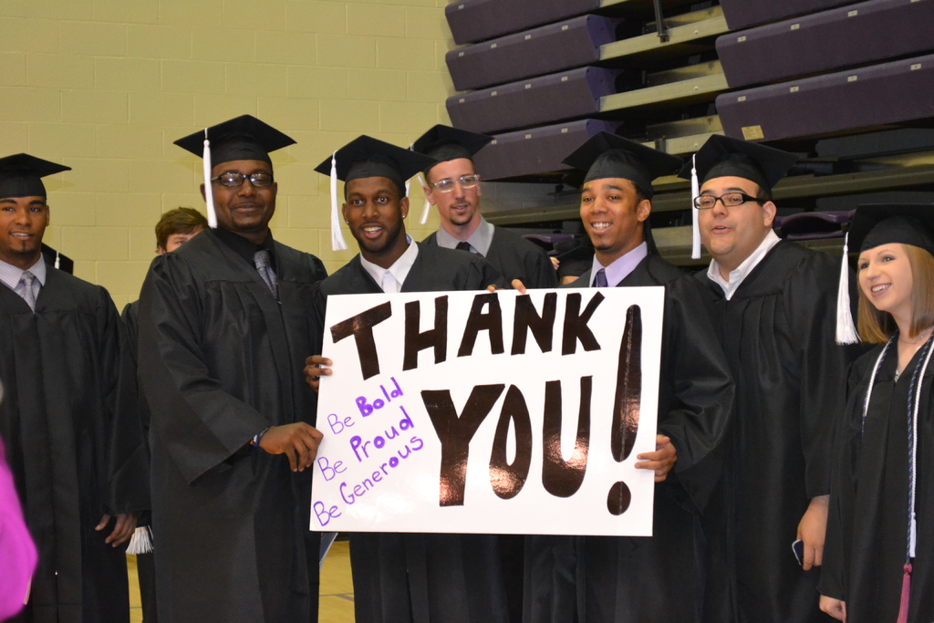 Eine Gruppe von Menschen, die in einer Reihe in der Bildmitte stehen und jeweils ein Plakat mit der Aufschrift 'Danke' halten.