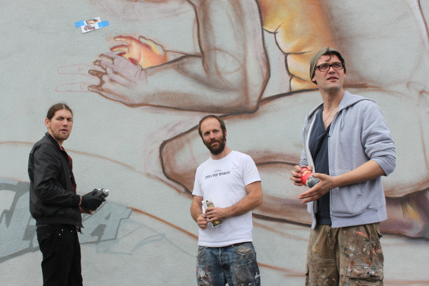 Menschen vor einer Graffiti-Wand mit Sprühdosen in der Hand