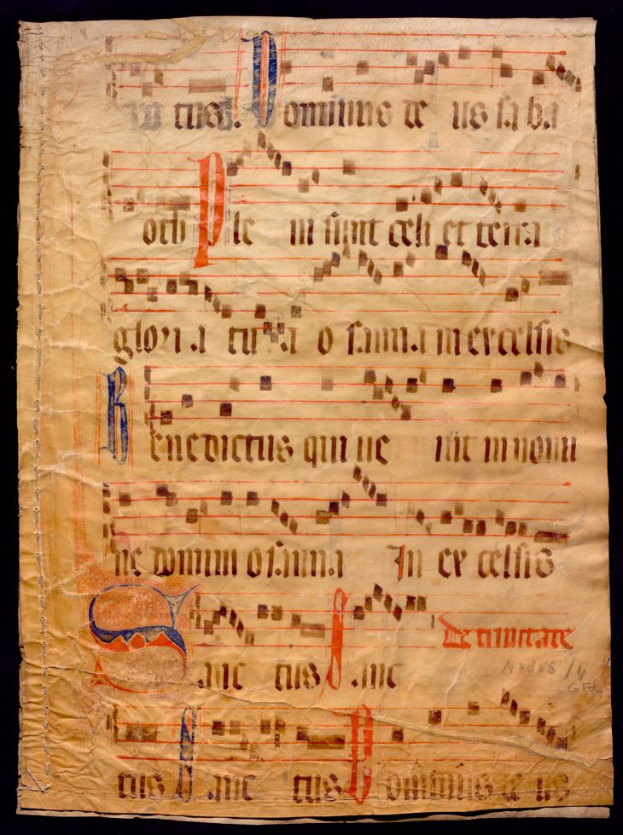 Ein illuminiertes Manuskript mit Musiknotation auf einem Blatt Papier vor einem dunklen Hintergrund, gefüllt mit Text und Musiksymbolen, die ein komplexes Design ergeben.