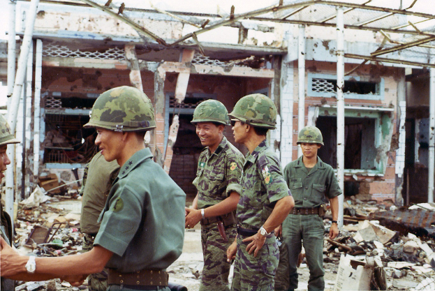 Ein demoliertes Haus mit einigen Soldaten in der Nähe.