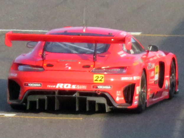 Roter Porsche 911 GTS Rennauto auf einer Rennstrecke mit aerodynamischem Design, großem Heckspoiler, breiten schwarzen Rädern und leistungsstarkem Motor.