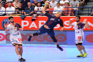 Eine Gruppe von Männern, die auf einem Platz Handball spielen, mit einem Ball in der Mitte, Zuschauern im Hintergrund und verstreuten Kleidungsstücken auf dem Platz, mit einem Banner mit der Aufschrift "Futsal-Weltmeisterschaft 2015 - Paris Saint-Germain vs. Olympique Lyon".