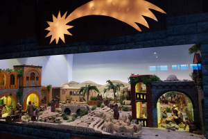 Eine Krippe in einem Museum, mit Menschen, Tieren, Häusern, Bäumen und anderen Gegenständen, beleuchtet von oben.