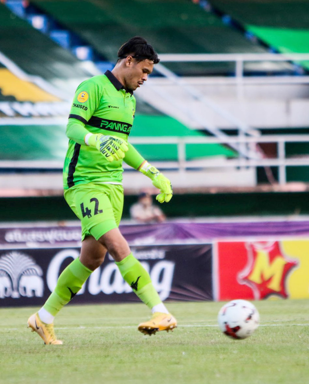 Ein Mann in grüner Torwarthose kickt einen Fußball auf einem Rasenfeld in einem Stadion, im Hintergrund sind Banner mit "Chivas USA vs Mexico City, 3-1, Copa Libertadores" zu sehen.