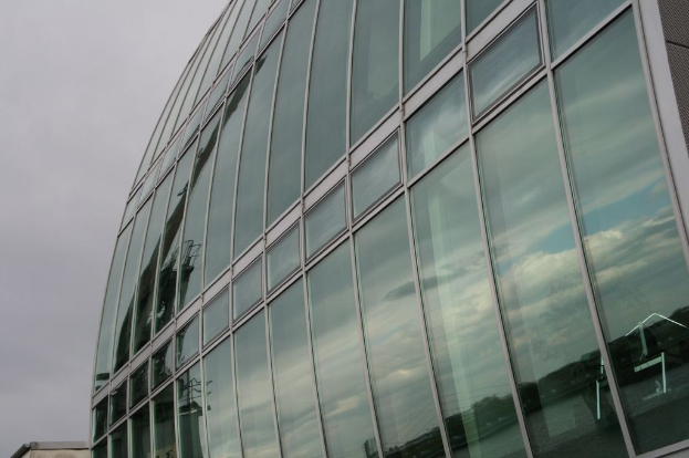 Ein großes Glas-Gebäude eines Unternehmens unter einem blauen Himmel.