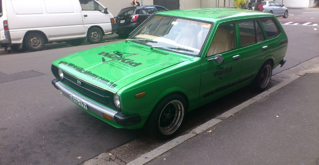 Eine Person steht am Straßenrand mit vorbeifahrenden Fahrzeugen.