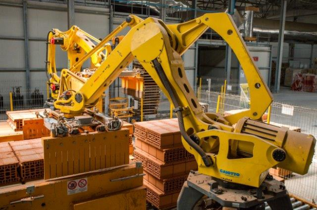 Ein großes Lager voller numerous Boxen, Kräne und verschiedene industrielle Ausrüstung, mit einem Zaun und Masten im Vordergrund und einer Wand im Hintergrund.