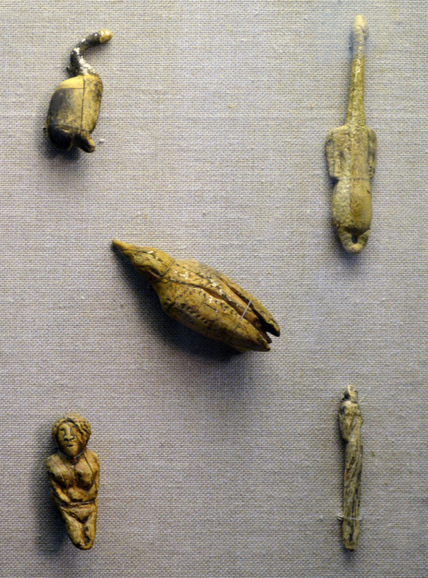 Eine Glasvitrine zeigt eine Sammlung von alten ägyptischen Artefakten, die auf einem Tuch arrangiert sind und feine Details aufweisen.