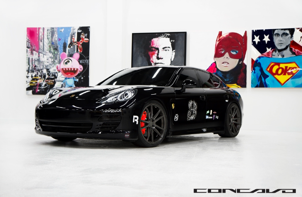 Ein schwarzer Nissan-Sportwagen steht vor Cartoon-Plakaten, mit einer kleinen Inschrift am unteren Bildrand.