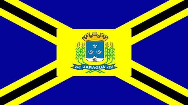 Die Flagge Jamaikas mit drei horizontalen Streifen in Schwarz, Gelb und Grün und einem mittigen Logo mit Text und Krone.