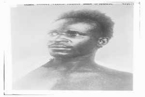 Ein Schwarz-Weiß-Foto eines Mannes mit ernster Miene, mit dem Text "Seneg Verletzter französischer Gefangener unter Deutschen" oben.