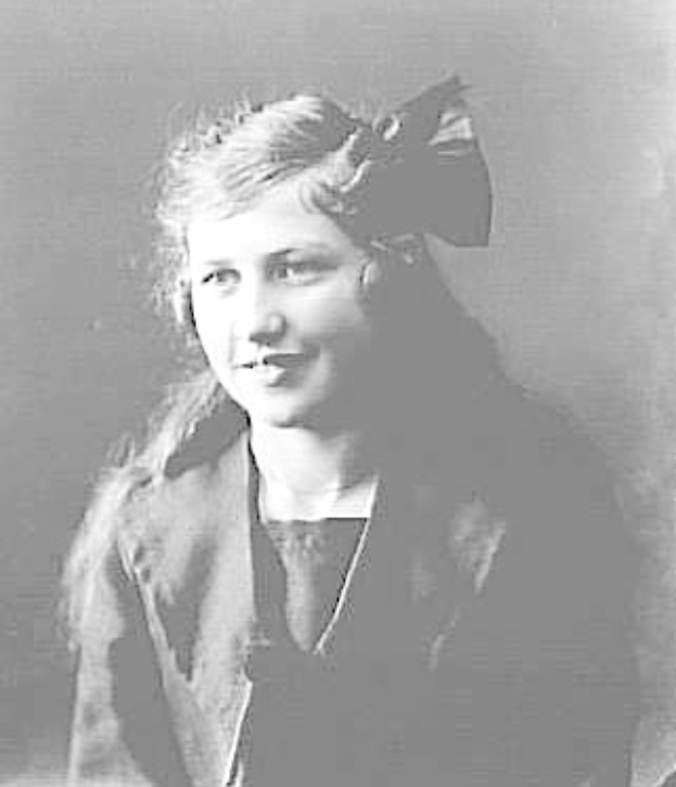 Ein Schwarz-Weiß-Foto eines jungen Mädchens mit einer Schleife im Haar, das lächelt, mit Text unten, der darauf hindeutet, dass es eine Suffragette ist.