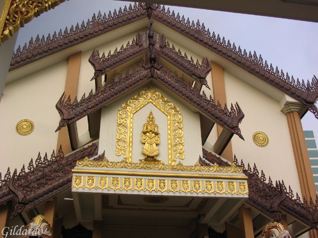 Ein Gebäude mit sculpturalen Elementen und zwei Statuen an seiner Basis, unter einem klaren Himmel.