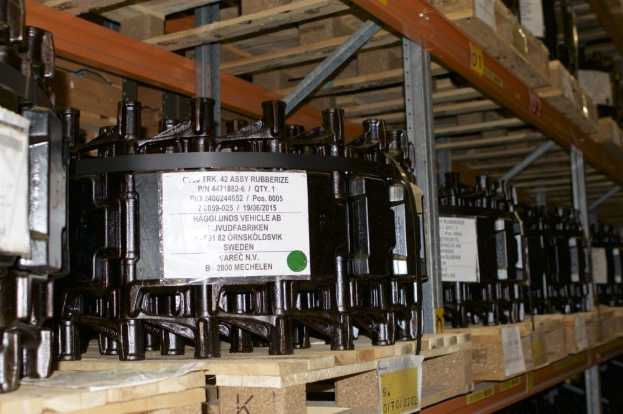 Ein Lagerraum voller Metallverteilergehäuse auf Holzpaletten, jedes mit einem Aufkleber versehen, der verschiedene Komponenten zeigt.